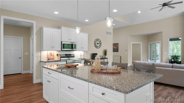 kitchen with stainless steel appliances, a center island, visible vents, and dark wood-type flooring