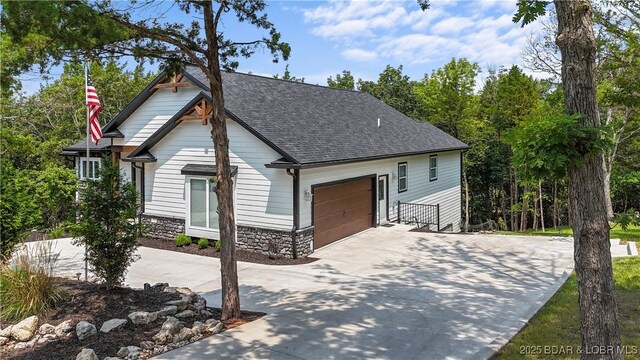 399 W End Cir, Osage Beach, MO 65065 - view of front of property with driveway, a shingled roof, an attached garage, and stone siding