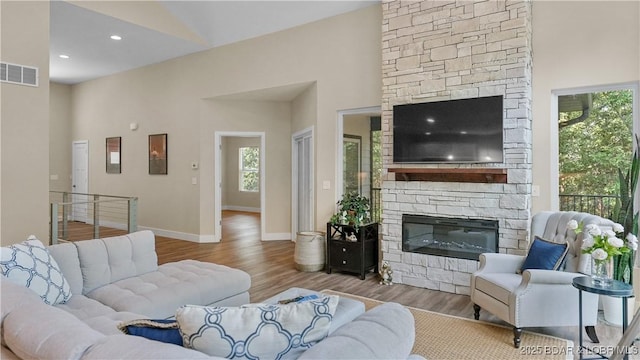 living area featuring recessed lighting, visible vents, a stone fireplace, wood finished floors, and baseboards