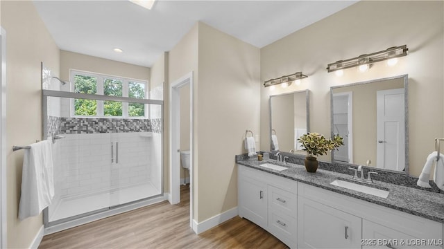 full bathroom featuring wood finished floors, a stall shower, a sink, and baseboards