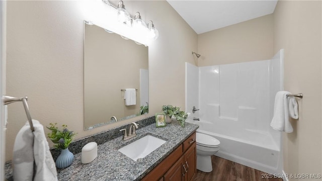 full bathroom featuring toilet, washtub / shower combination, wood finished floors, and vanity