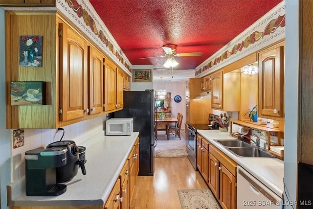 kitchen featuring white appliances, a ceiling fan, a textured ceiling, light wood-style floors, and a sink