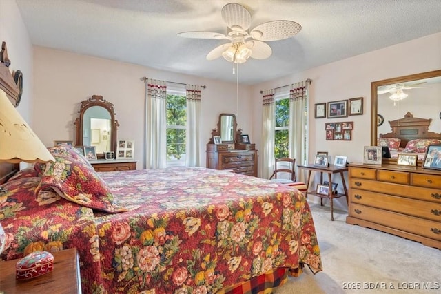 carpeted bedroom with a ceiling fan, multiple windows, and a textured ceiling