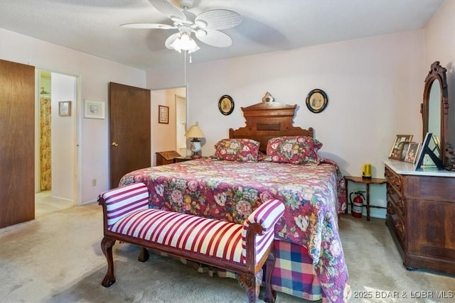 bedroom featuring a ceiling fan, light colored carpet, and ensuite bath