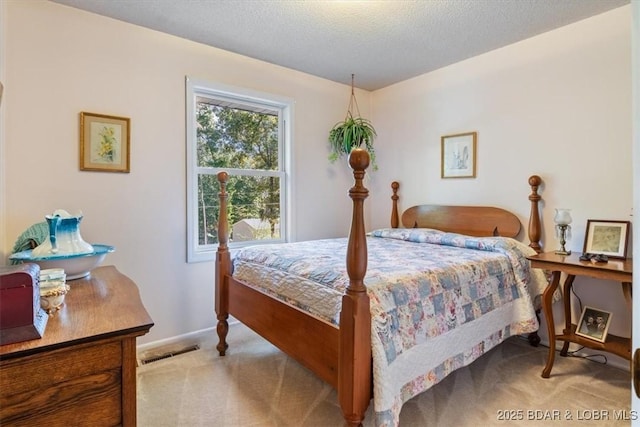 bedroom with a textured ceiling, baseboards, visible vents, and light colored carpet