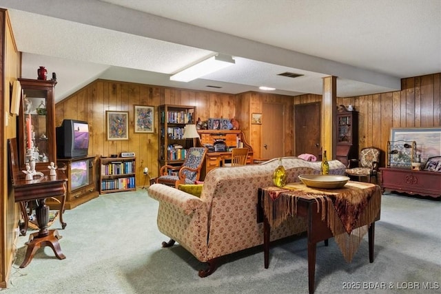 carpeted living room with visible vents and wooden walls