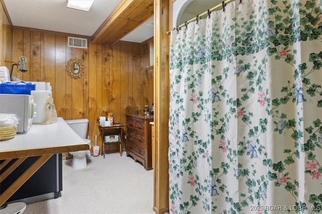 full bathroom featuring curtained shower, visible vents, wooden walls, and toilet