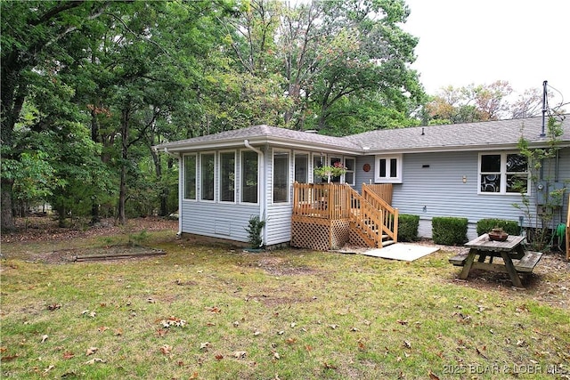 rear view of house with a lawn, a wooden deck, and a sunroom