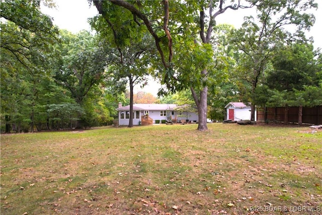 view of yard with an outbuilding, fence, and a storage shed