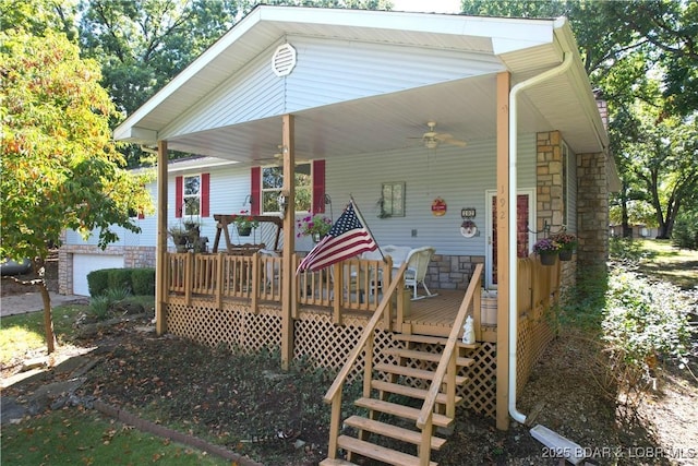 exterior space featuring a garage, stone siding, ceiling fan, and a wooden deck