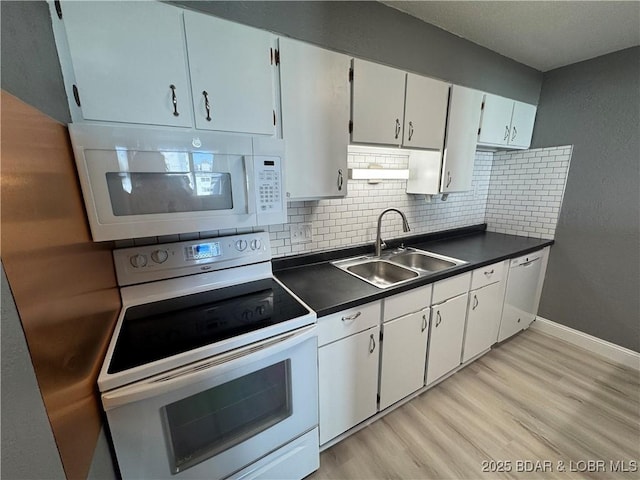 kitchen featuring dark countertops, white appliances, a sink, and decorative backsplash