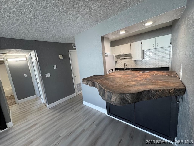 kitchen with dark countertops, light wood finished floors, white cabinetry, and a sink