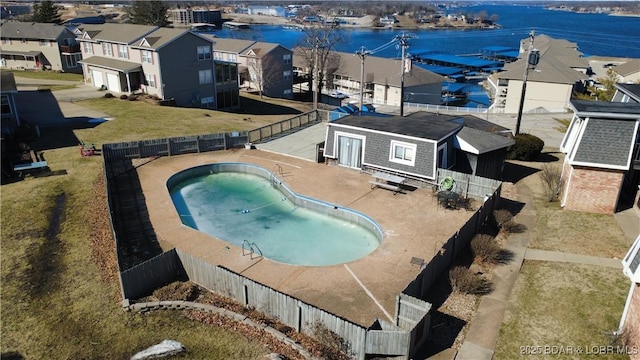 view of pool featuring a water view, a patio area, a fenced backyard, and a residential view