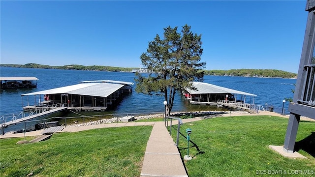 view of dock with a water view and a lawn