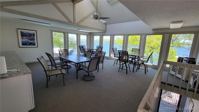 sunroom / solarium featuring a water view, plenty of natural light, ceiling fan, and lofted ceiling