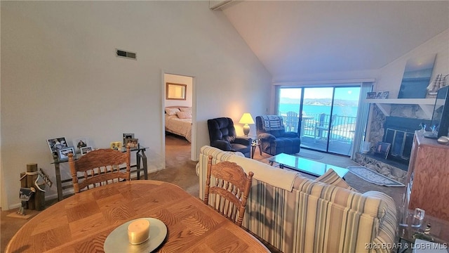 carpeted dining room featuring high vaulted ceiling, visible vents, and a fireplace