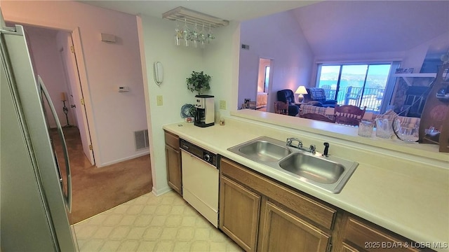 kitchen with light countertops, visible vents, vaulted ceiling, a sink, and dishwasher