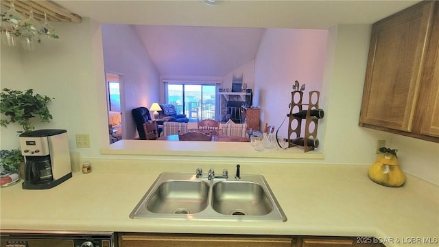 kitchen with lofted ceiling, black dishwasher, light countertops, and a sink