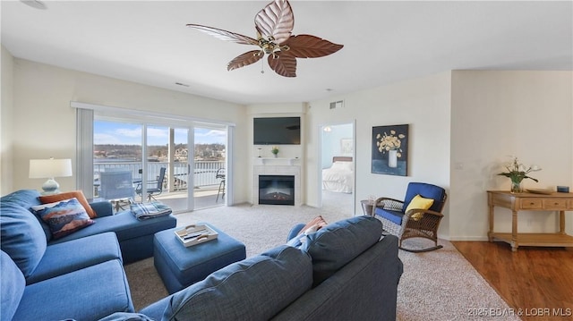 living area with baseboards, visible vents, ceiling fan, wood finished floors, and a fireplace