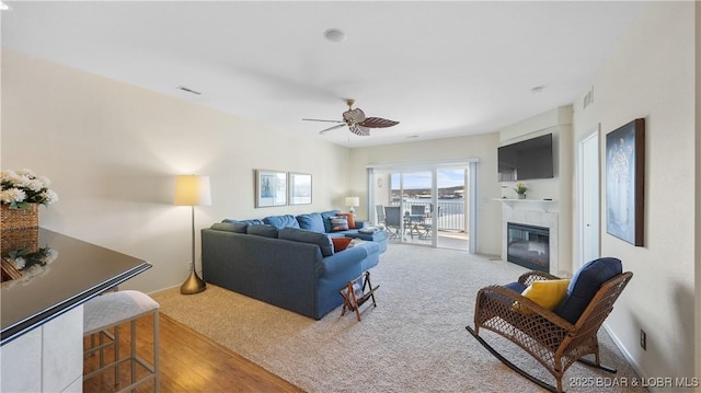 carpeted living room featuring visible vents, ceiling fan, and a tiled fireplace