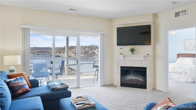 carpeted living area featuring a tile fireplace, visible vents, and baseboards