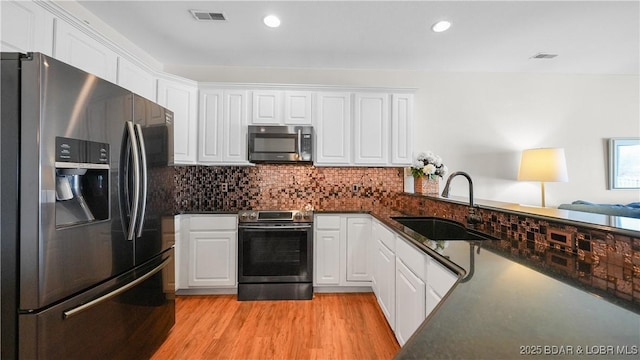 kitchen with stainless steel appliances, a sink, visible vents, and white cabinets