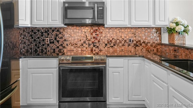 kitchen featuring appliances with stainless steel finishes, dark countertops, white cabinetry, and backsplash