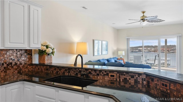 kitchen featuring dark countertops, white cabinetry, a sink, and decorative backsplash