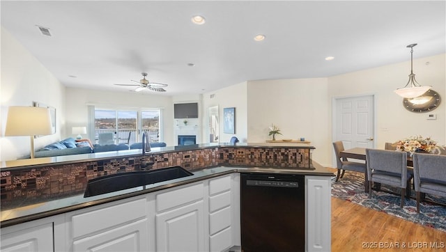 kitchen with dark countertops, visible vents, open floor plan, a sink, and dishwasher