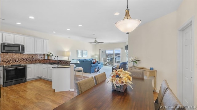 dining room with light wood-style floors, a ceiling fan, and recessed lighting