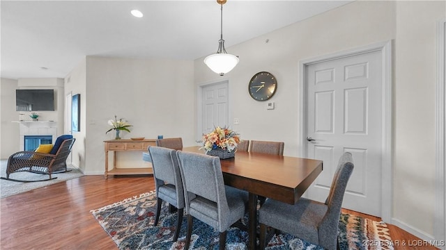 dining room featuring baseboards, wood finished floors, and a tile fireplace