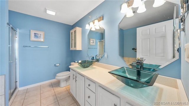 bathroom featuring a stall shower, tile patterned flooring, a sink, and double vanity