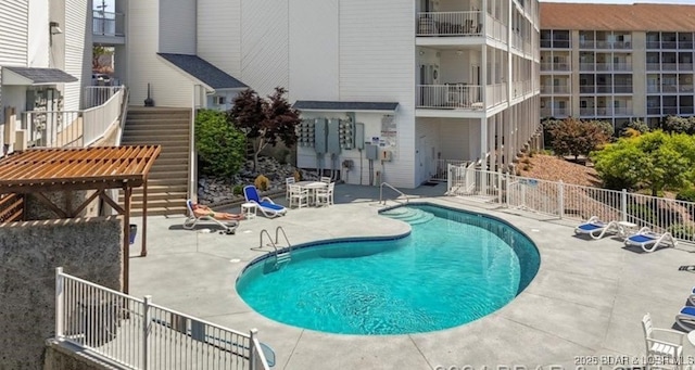 community pool with a patio, stairway, and fence