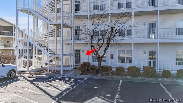 view of property with stairs and uncovered parking