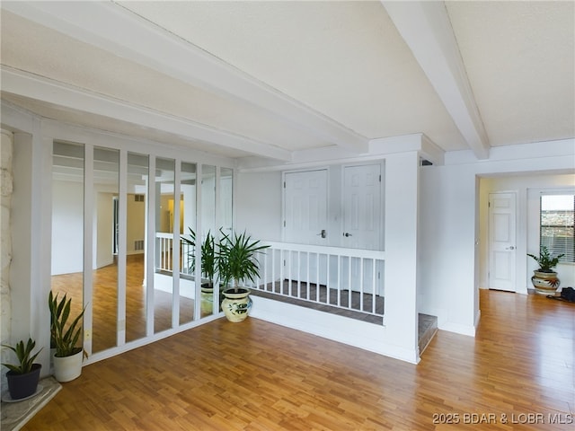 unfurnished room featuring beamed ceiling, wood finished floors, and baseboards