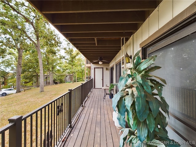 wooden terrace featuring ceiling fan and a yard