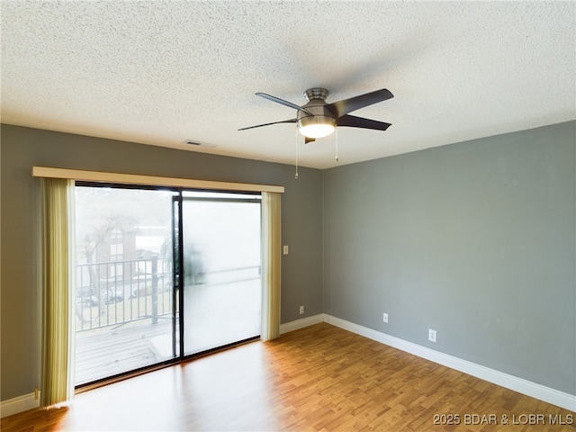 empty room featuring visible vents, a textured ceiling, baseboards, and wood finished floors