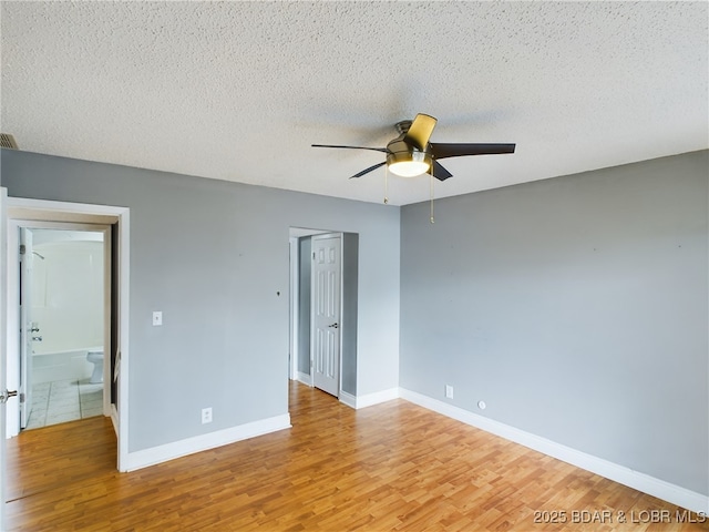 unfurnished bedroom featuring visible vents, baseboards, ceiling fan, wood finished floors, and a textured ceiling