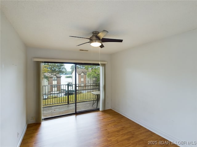 spare room with ceiling fan, a textured ceiling, baseboards, and wood finished floors