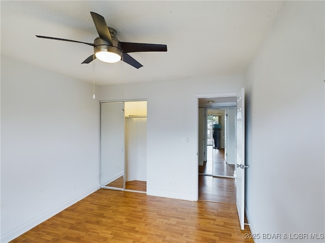 unfurnished bedroom with ceiling fan, a closet, light wood-type flooring, and baseboards