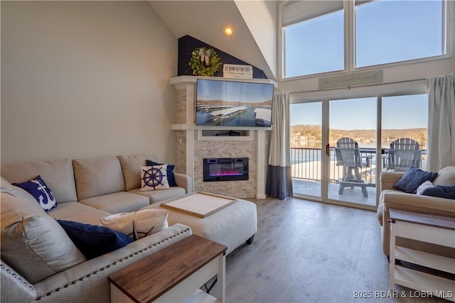 living room featuring high vaulted ceiling, a glass covered fireplace, and wood finished floors