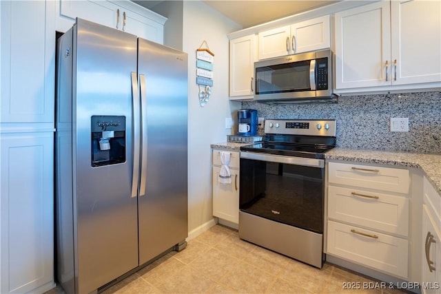 kitchen with light tile patterned floors, decorative backsplash, light stone countertops, stainless steel appliances, and white cabinetry