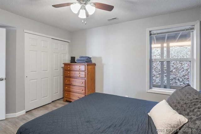 bedroom with a closet, visible vents, a ceiling fan, a textured ceiling, and wood finished floors