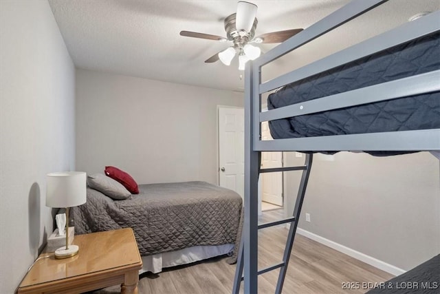 bedroom with ceiling fan, a textured ceiling, baseboards, and wood finished floors