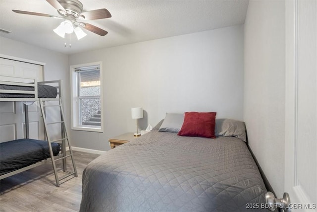 bedroom with visible vents, a ceiling fan, a textured ceiling, wood finished floors, and baseboards