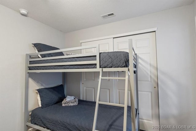 bedroom featuring a textured ceiling, a closet, and visible vents