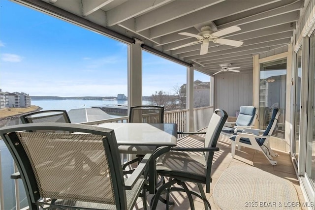 balcony with outdoor dining area, a water view, and a ceiling fan