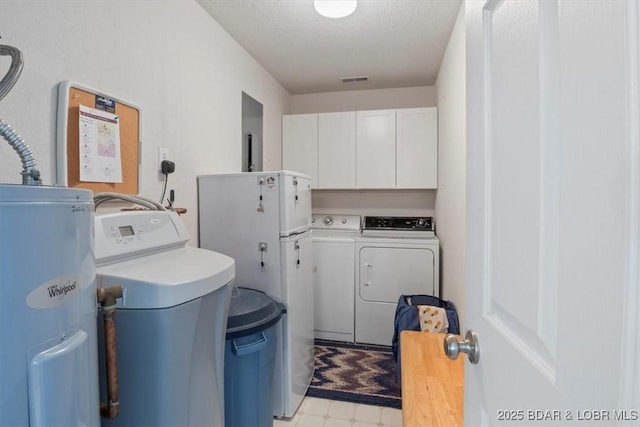 laundry area featuring cabinet space, electric water heater, a textured ceiling, washer and dryer, and light floors