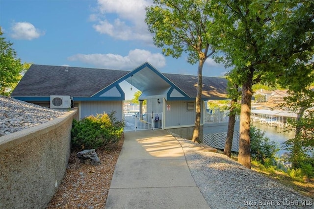 view of front facade with a shingled roof and a gate