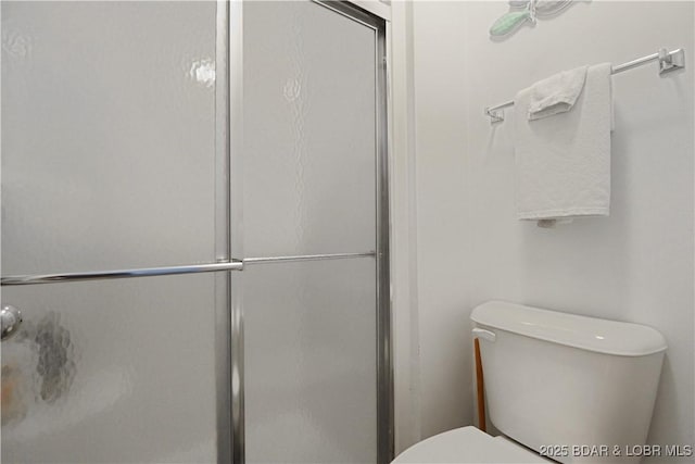 bathroom featuring a shower with shower door and toilet